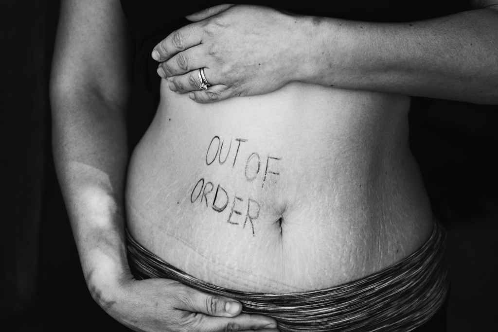 The image shows a woman's belly with 'out of order' written on it. 5 Easy Ways to help relieve bloating.